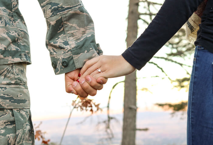 Military Man and civilian wife holding hands in the mountains.