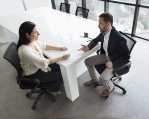 Human Resources professional at a desk interviewing a candidate for a job.
