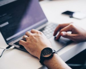 Man typing on a laptop taking IT classes online.