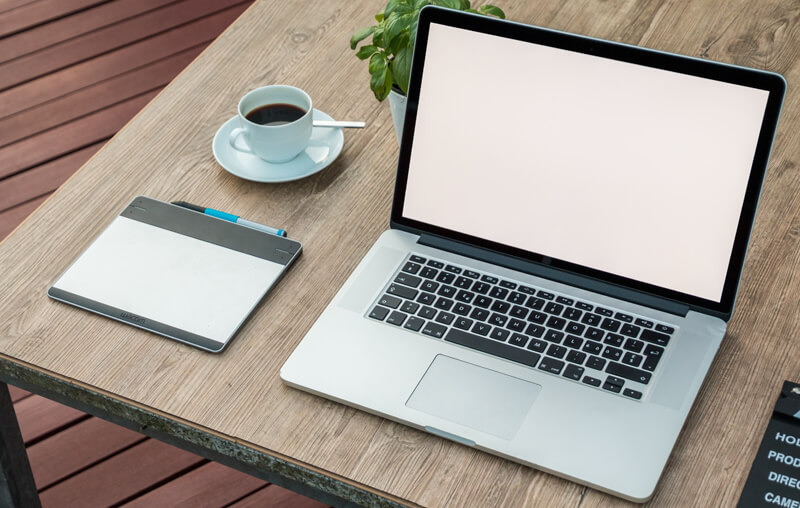 A remote job station with laptop and coffee.