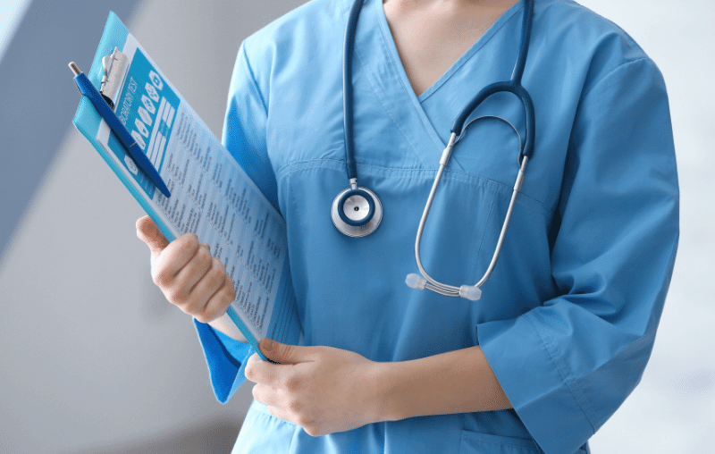 medical assistant in scrubs holding clipboard