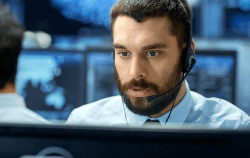 young man sitting behind computer with headset microphone on