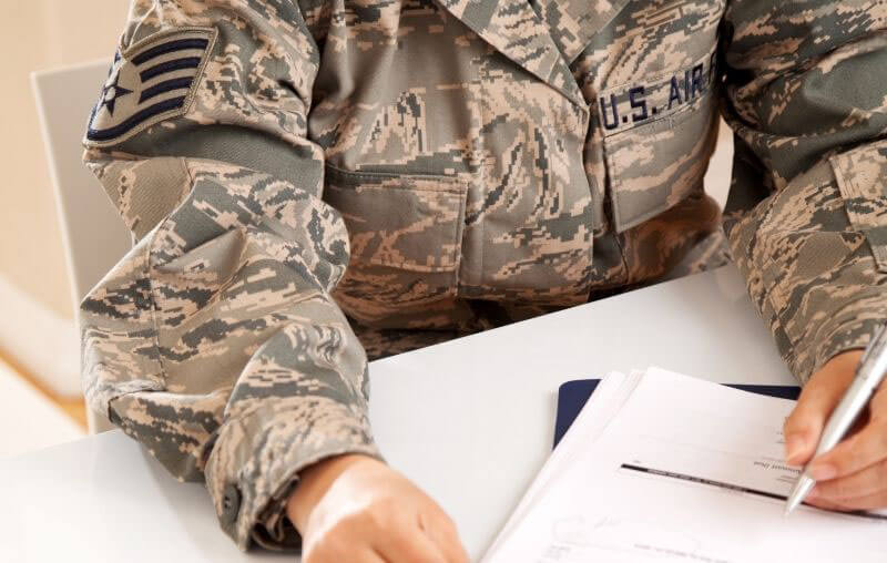military man signing benefits documents